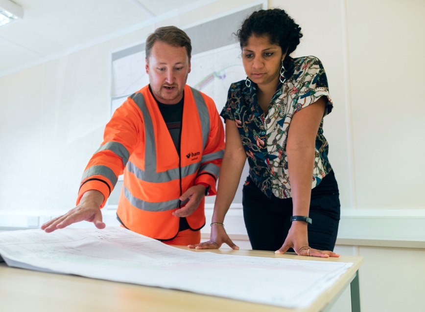 Two workers discuss a set of construction plans.